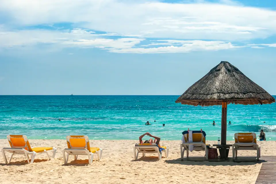 Palapa umbrella and lounge chairs on the white sand beach of Cancun with turquoise Caribbean water
